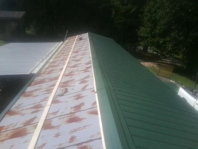 Old rusted panels beside newly installed green metal roofing — Wind Damage Roof Repair by Roofing Brothers in Leicester