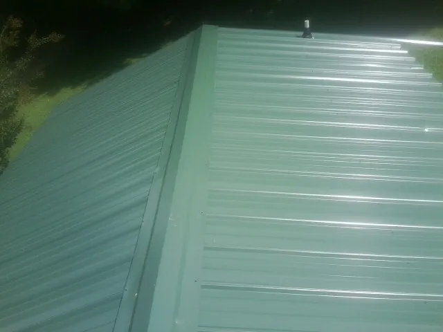 New green metal panels meeting at the ridge of a roof — Flat Roof Repair work by our crew in Leicester